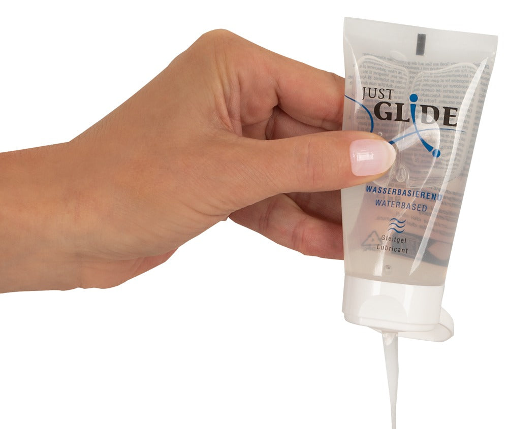 Just Glide water-based lubricant bottle with clear label and pump dispenser on a neutral background.